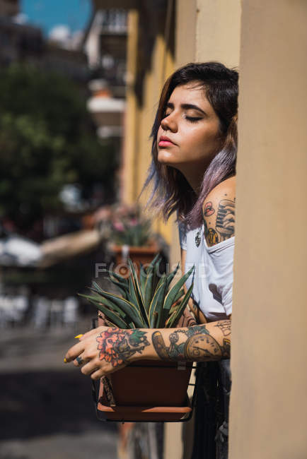 Jovem mulher de pé na varanda e desfrutar do sol — Fotografia de Stock