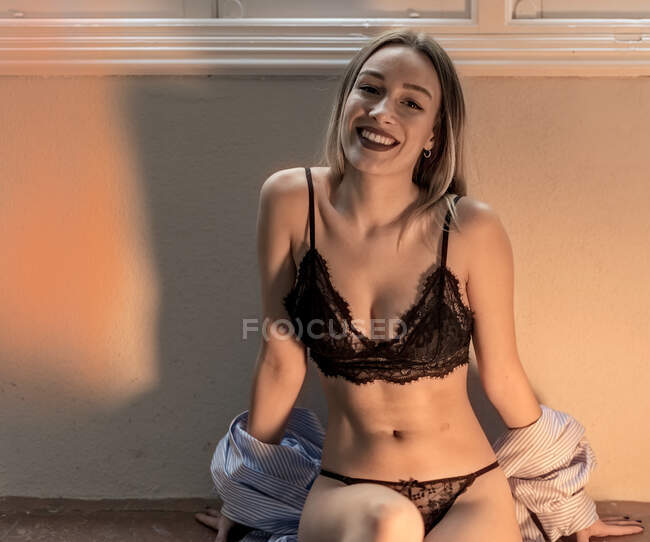 Woman in bra sitting in dark room — Stock Photo