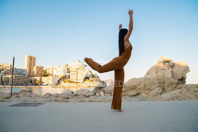 Playful woman in stylish overall making splits on shore — Stock Photo