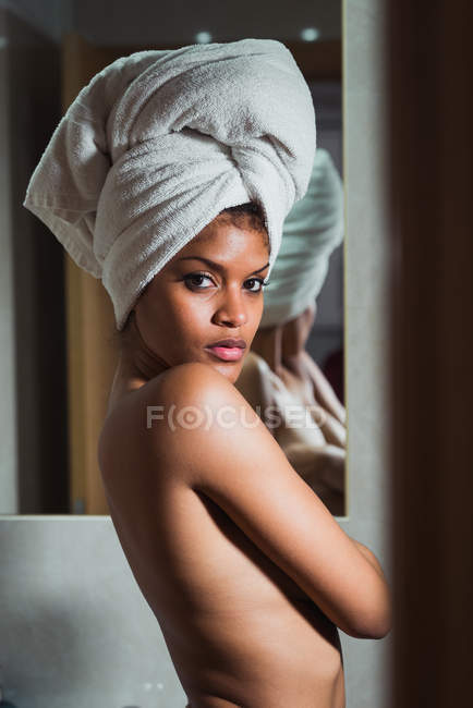 Femme seins nus séduisante avec serviette sur la tête debout dans la salle de bain — Photo de stock