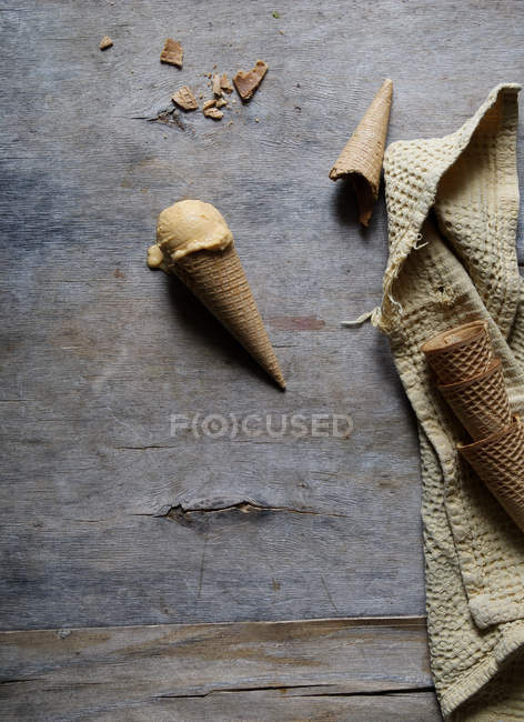Вкусное мороженое в хрустящем сахарном конусе на сером деревянном столе — стоковое фото