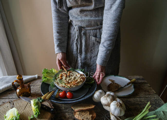 Hände nehmen Teller mit köstlichem Artischockenhummus — Stockfoto