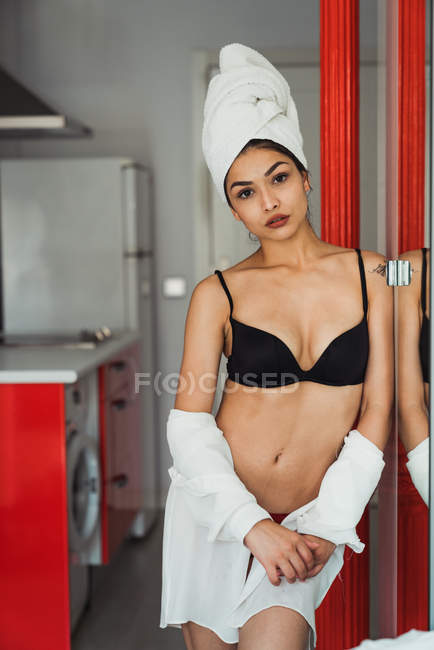 Sinnliche junge Frau in Dessous und Handtuch auf dem Kopf zu Hause stehend und in die Kamera blickend — Stockfoto