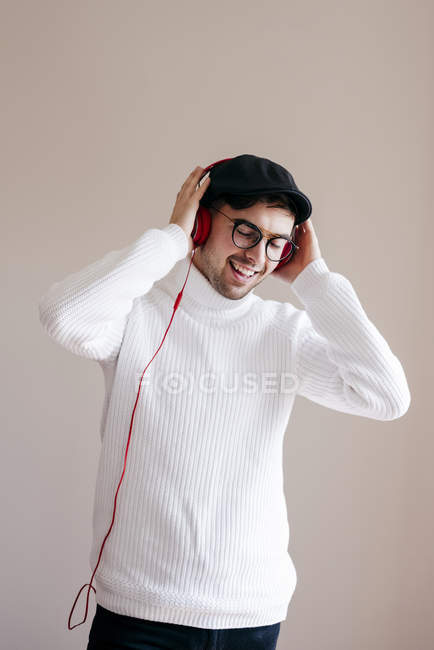 Hombre casual con auriculares de pie sobre fondo gris - foto de stock