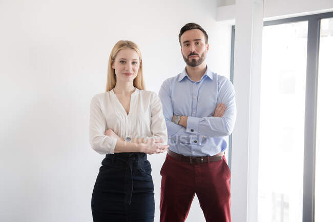 Colleagues standing with crossed arms and looking at camera — Stock Photo