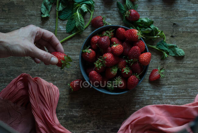 Prendre à la main de délicieuses fraises du bol — Photo de stock