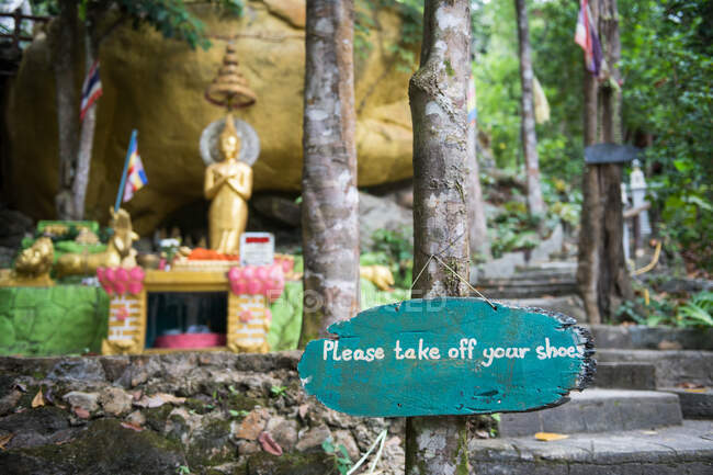 Por favor, quítese los zapatos letrero de madera en estatua de Buda de oro en Tailandia. - foto de stock