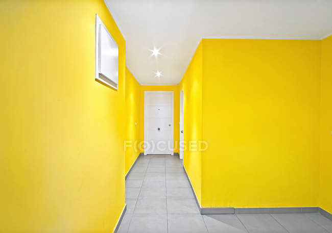 Желтые стены и белые двери узкого коридора в современном здании — стоковое фото