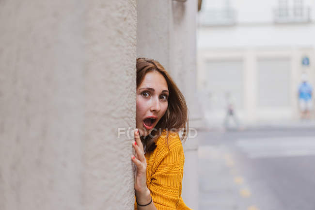 Überraschte junge Frau lehnt auf der Straße an Mauer — Stockfoto