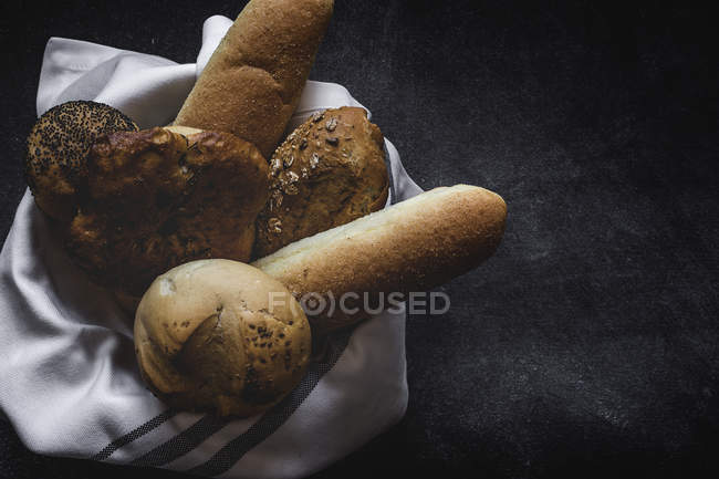 Pains de pain fraîchement cuits sur du tissu sur fond noir — Photo de stock
