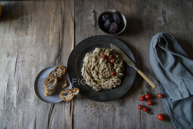 Artischocken-Dip serviert mit Kirschtomaten auf schwarzem Teller auf rustikalem Holztisch — Stockfoto