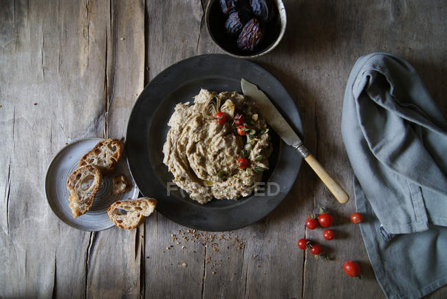 Artichoke dip served with cherry tomatoes in black plate on rustic wooden table — Stock Photo