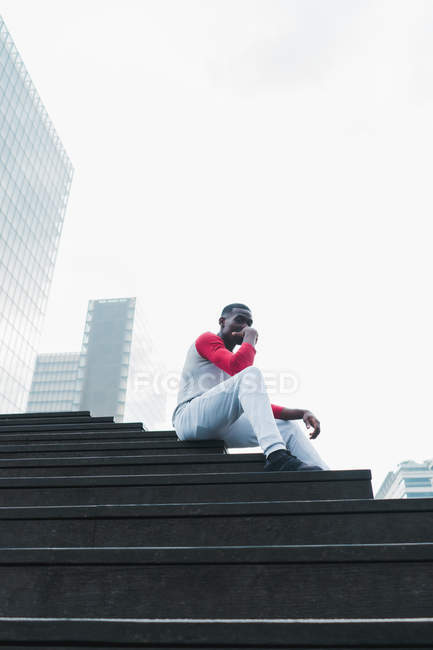Sportlicher ethnischer Mann entspannt auf Außentreppe — Stockfoto
