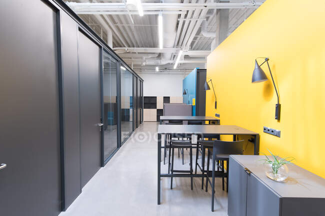 Hall avec des tables et des lampes sur des murs colorés dans un design moderne de bureau contemporain léger — Photo de stock