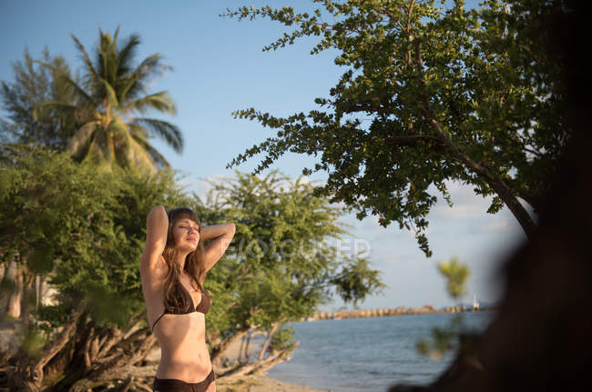 Молодая женщина отдыхает с закрытыми глазами на берегу моря в Таиланде — стоковое фото