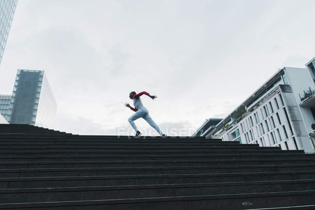 Ethnic sportsman running upstairs in city — Stock Photo