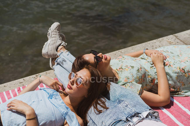 Усміхнені друзі-жінки в сонцезахисних окулярах розслабляються на набережній — стокове фото