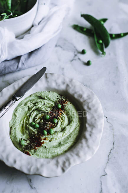From above shot of ceramic bowl with delicious mashed peas standing on white marble background — Stock Photo