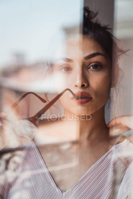 Close-up of alluring woman holding glasses with mouth slightly opened behind glass — Stock Photo
