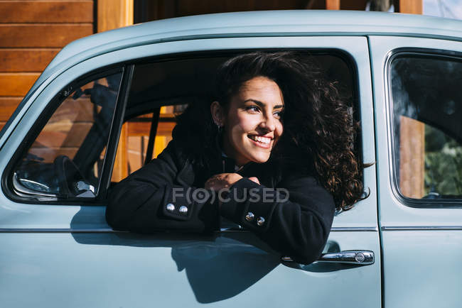 Молода жінка сидить всередині старої машини на сонячному світлі — стокове фото