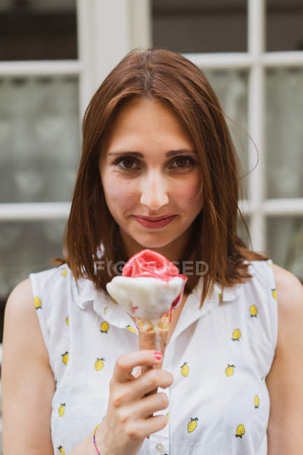Молодая женщина в узорчатом топе держит мороженое на открытом воздухе — стоковое фото