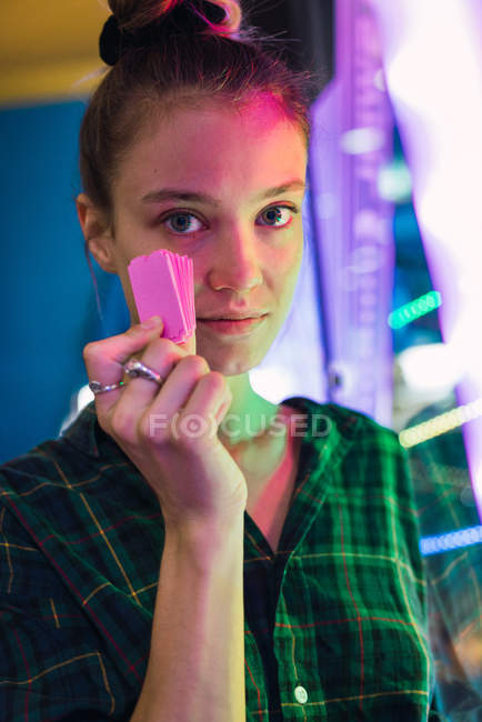 Mujer joven mostrando entradas arcade y mirando a la cámara - foto de stock