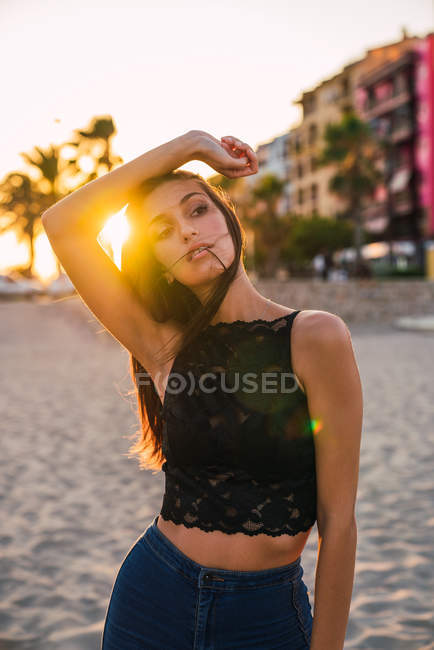 Wunderschöne brünette Frau posiert am Strand bei Sonnenuntergang — Stockfoto
