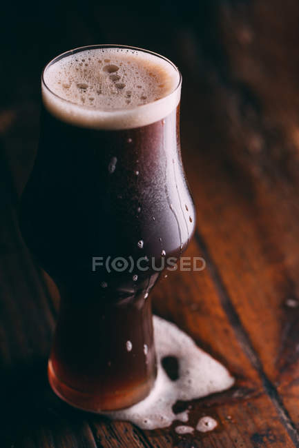 Ставлене пиво в склянці на темному дерев'яному столі — стокове фото