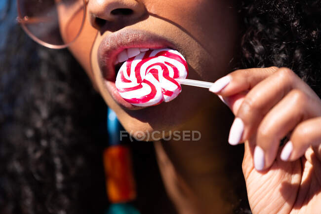 Beautiful black woman wearing sunglasses and holding a lollipop — Stock Photo