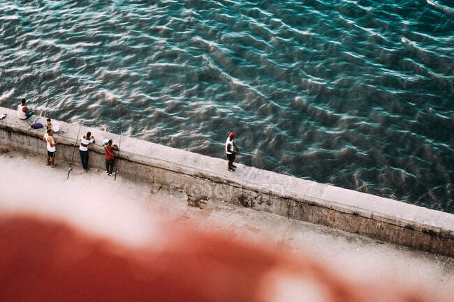 Von oben Aufnahmen von Männern auf der Küste der Steinstadt beim Angeln im blauen Ozeanwasser Kubas. — Stockfoto