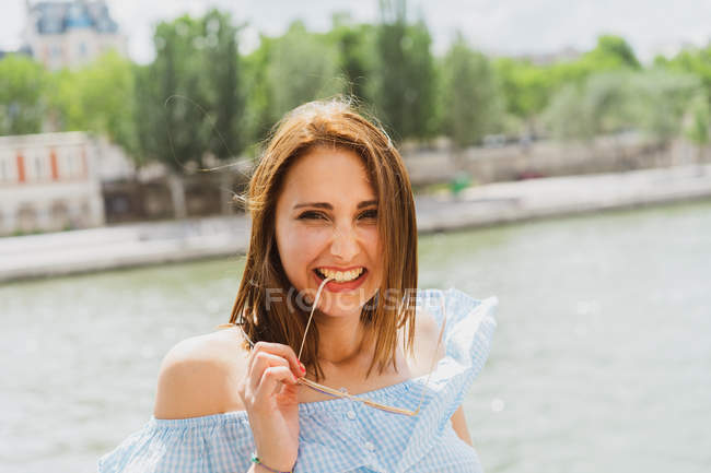 Jeune femme drôle grimaçant tout en se tenant debout au bord de l'eau — Photo de stock