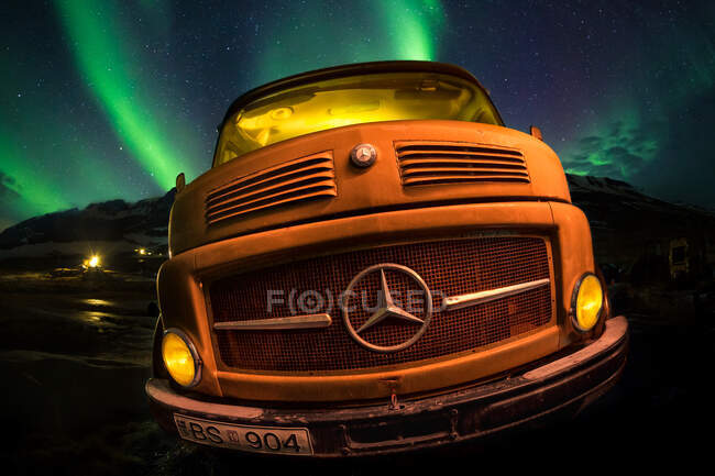 Voiture rétro debout sur fond de magnifiques aurores boréales en Islande. — Photo de stock
