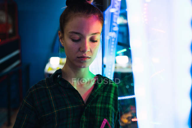 Жінка в картатій сорочці, дивлячись вниз в освітленій кімнаті — стокове фото
