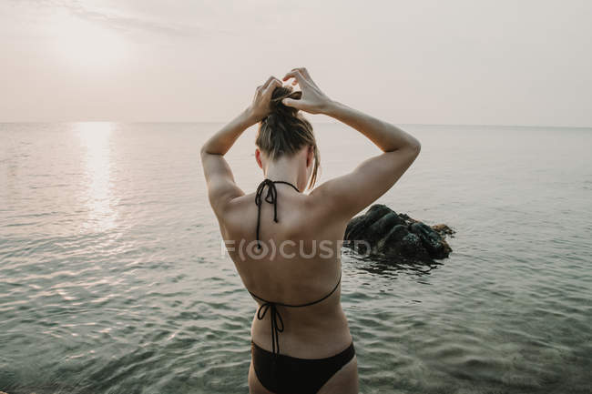 Жінка в купальнику, що стоїть в океані під час заходу сонця — стокове фото