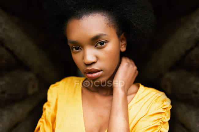 Afrikanisch-amerikanische Frau in leuchtend gelbem Kleid blickt in die Kamera auf braunem Hintergrund — Stockfoto