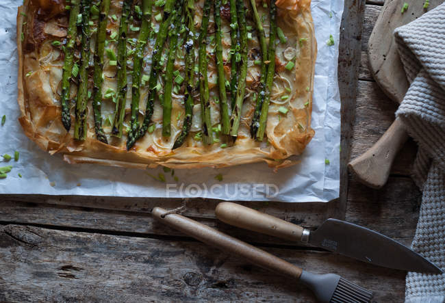Запечений спаржевий пиріг на дерев'яній поверхні з ножем і пензлем — стокове фото