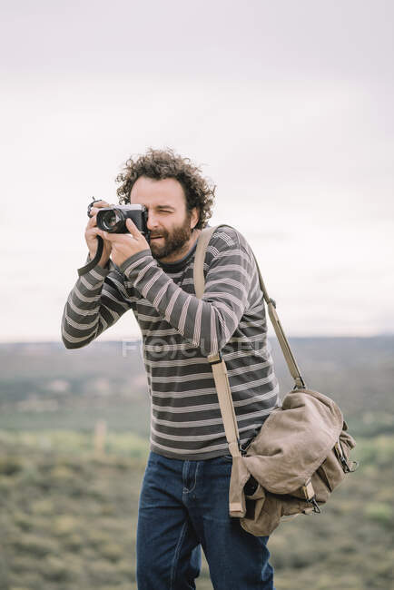 Hombre fotoperiodista posa con su cámara fotográfica - foto de stock