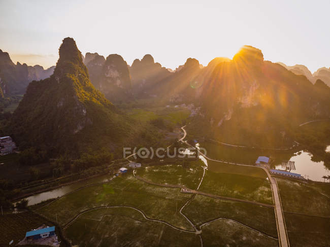 Campos y ciudad rodeada de montañas rocosas únicas al atardecer, Guangxi, China - foto de stock