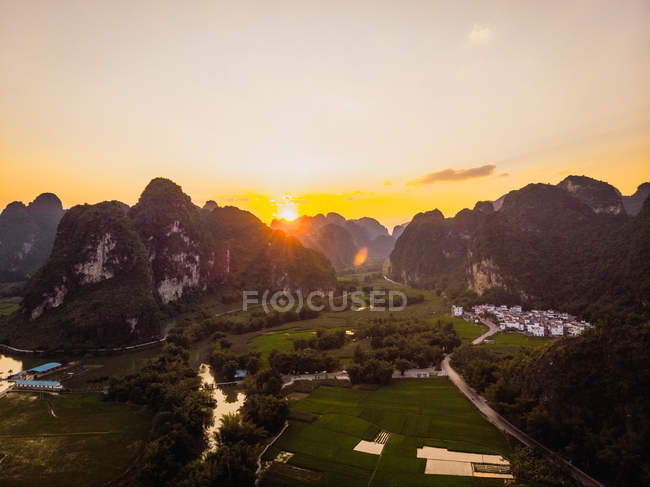 Felder und Stadt umgeben von einzigartigen felsigen Bergen bei Sonnenuntergang, Guangxi, China — Stockfoto