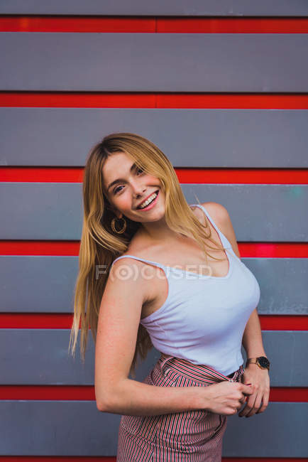 Блондинка молода жінка в повсякденному вбранні стоїть на смугастій стіні — стокове фото