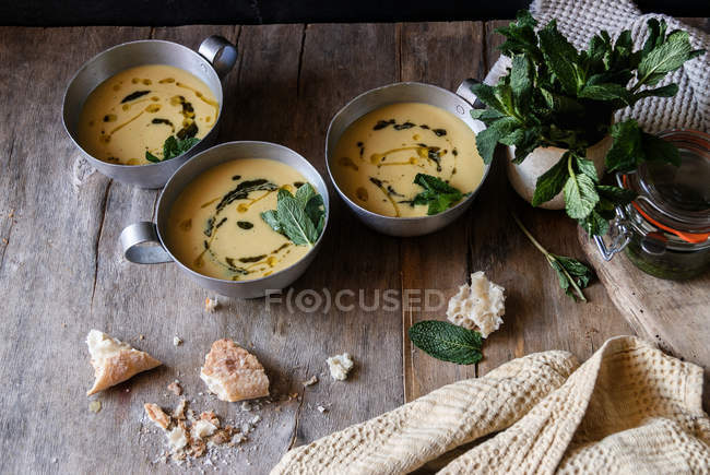 Corn cream soup with coconut and pesto in bowls on wooden table — Stock Photo
