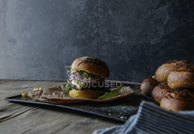 Hamburger saporito con lenticchia e carota viola su vassoio con pergamena — Foto stock