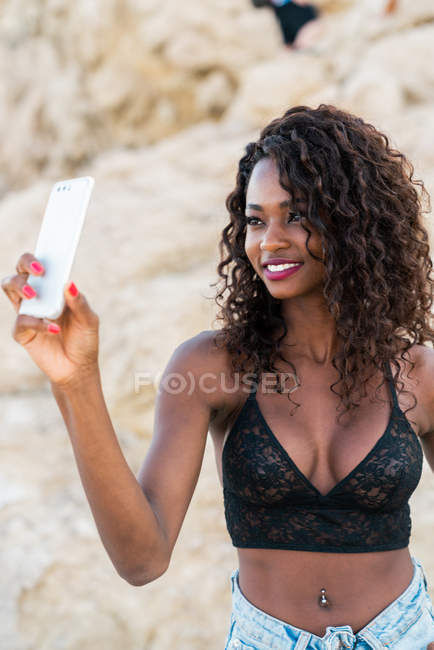 Cheerful pretty black woman taking selfie outside — Stock Photo