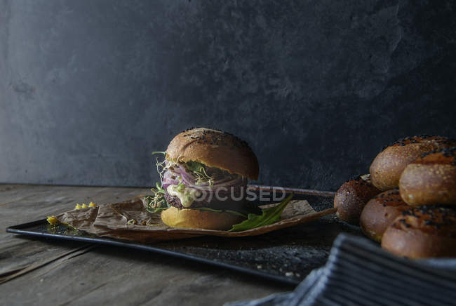 Sabrosa hamburguesa con lentejas y zanahoria púrpura en bandeja con pergamino - foto de stock