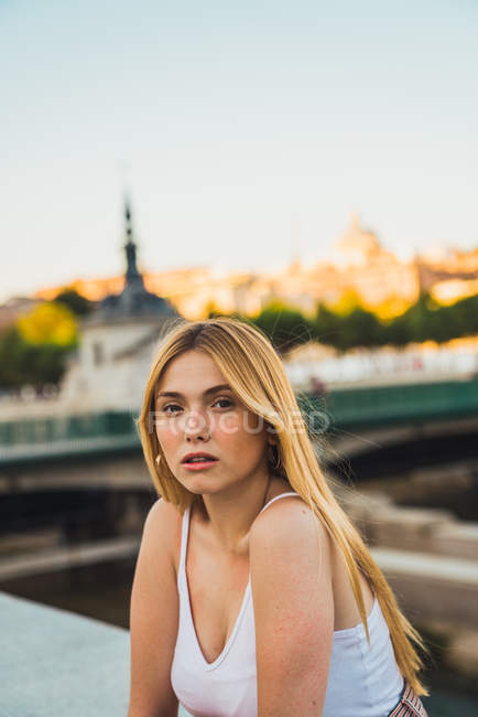 Bionda giovane donna in abito casual guardando la fotocamera mentre seduto in città — Foto stock