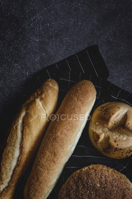 Panes recién horneados sobre tela negra - foto de stock