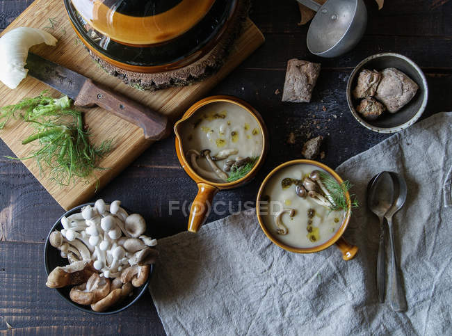 Подається в мисках смачний грибний крем на сільському дерев'яному столі з інгредієнтами — стокове фото