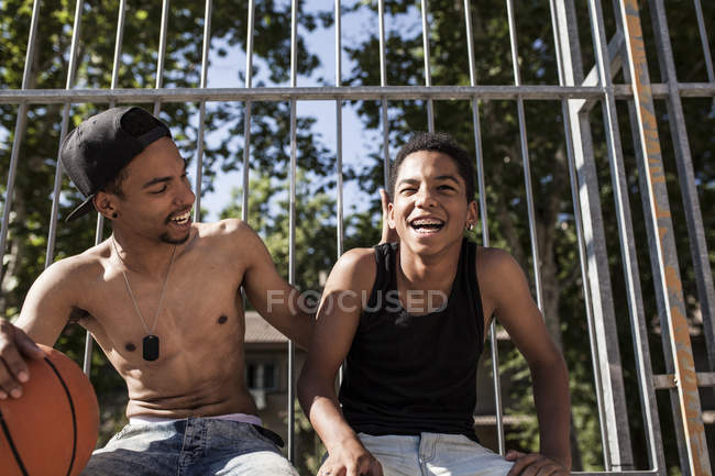 Афро молодые братья сидят с баскетболом на открытом воздухе и обнимаются — стоковое фото