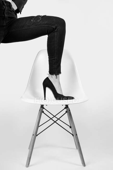 Donna con il piede in posa su una sedia di design con tacchi alti — Foto stock