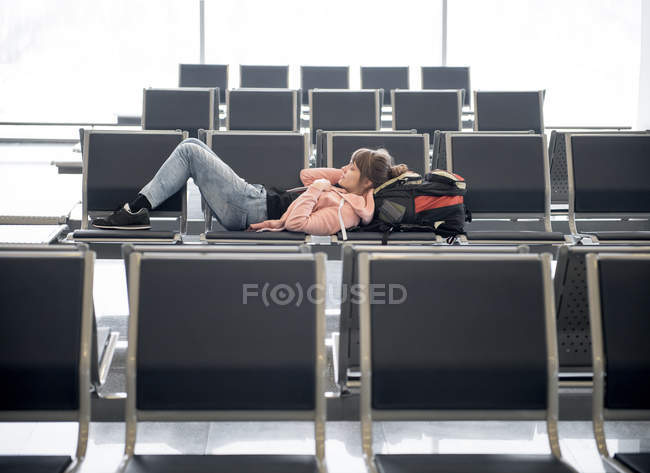 Touristin liegt und ruht auf Bank im Terminal des Flughafens — Stockfoto